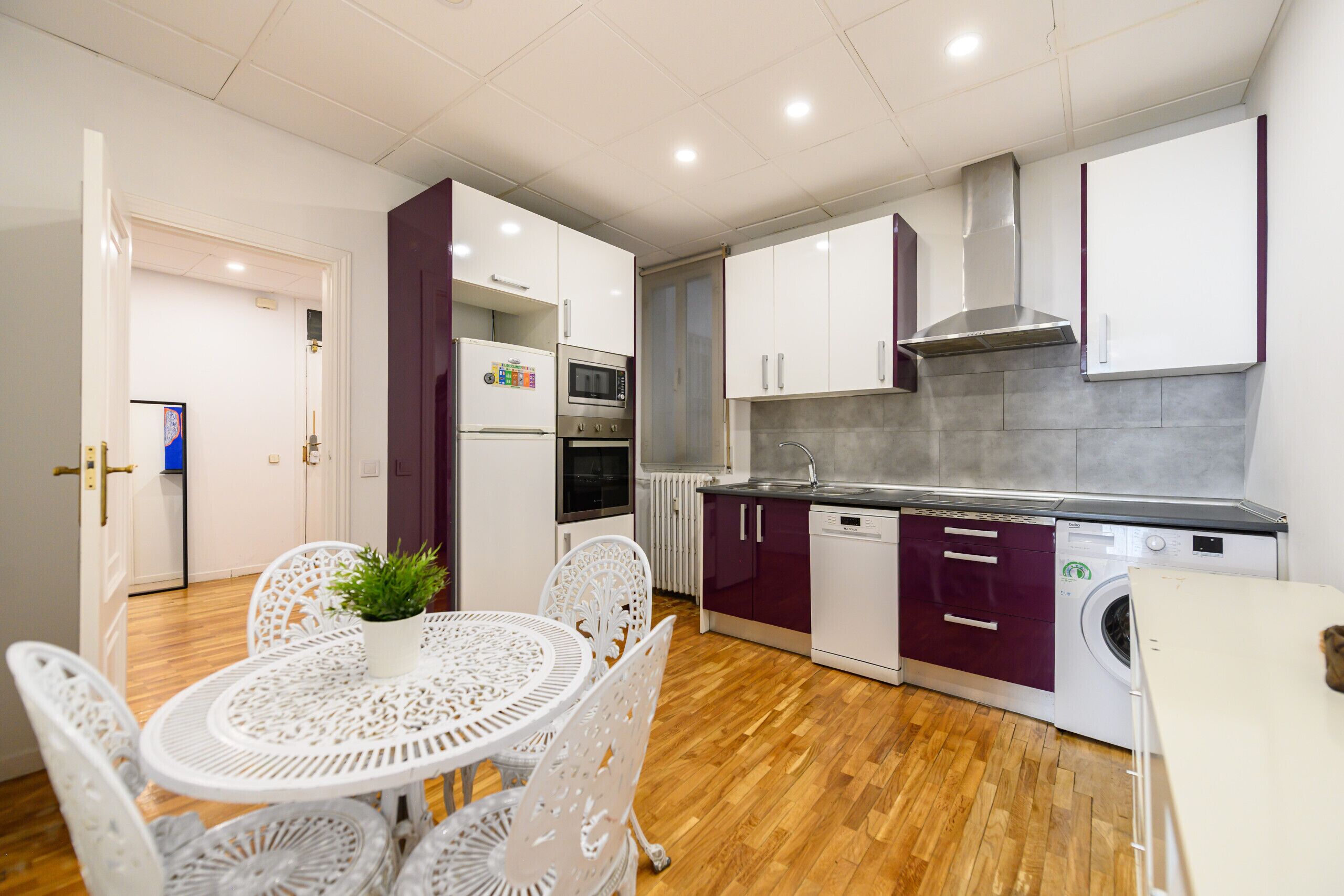 Cocina compacta con alacenas blancas, horno integrado y lavadora.