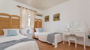 Une chambre avec deux lits, une coiffeuse avec un miroir et un petit tabouret.