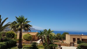 A coastal property with a view of the sea, surrounded by palm trees and a stone wall. - Lisca Blu villa 6+2 pp, seaside, A/C, Wifi, free parking and 2 bathrooms. Dogs allowed (Custonaci)