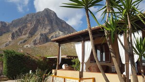 A mountain view from a covered outdoor area with a wooden bench and a wicker chair. - Lisca Blu villa 6+2 pp, seaside, A/C, Wifi, free parking and 2 bathrooms. Dogs allowed (Custonaci)