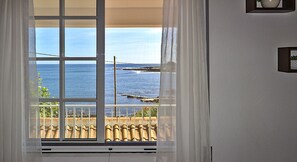 Une fenêtre donnant sur la mer et un toit recouvert de tuiles.