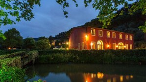 A large red building with arched windows and a reflection in the water. - Casa Matteucci     . (Capannori)