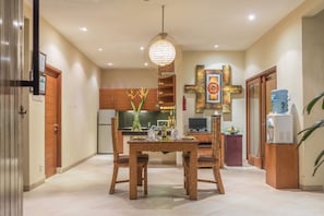 Enjoy meals in the central dining area with a wooden table and chairs, illuminated by a unique pendant light.