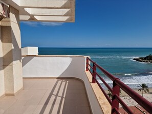 Un balcon avec vue sur l’océan et une côte rocheuse.