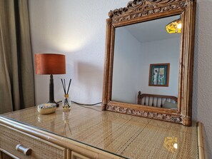 A mirror with an ornate wooden frame, a lamp with a brown shade, and a small decorative item on a textured surface. - A07 EDIFICIO ZAFIRO 212D (Calpe)