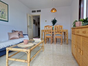 Un salon comprenant un canapé, une table basse, une table à manger avec des chaises et un buffet.