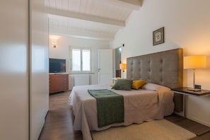 Relax in this serene bedroom with a large bed and a mounted TV, complemented by a dresser and framed artwork.