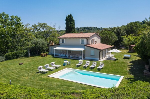 Une maison à deux étages avec une piscine, un espace salon extérieur et un jardin.