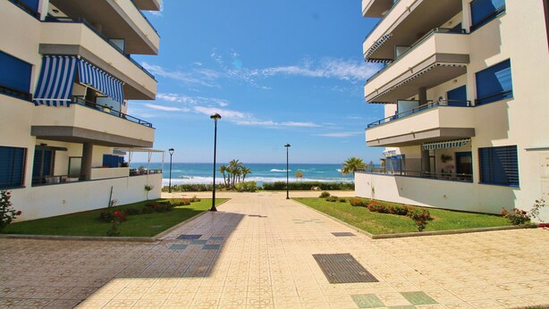 Un camino que lleva a un hotel frente a la playa, con balcones y vistas al océano.