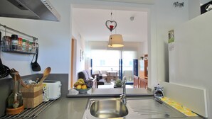 Una cocina moderna con un lavamanos de acero inoxidable, un frutero y una lámpara colgante.