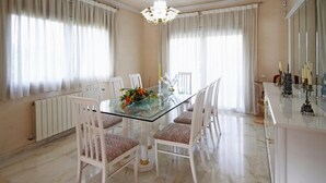Un coin repas avec une table en verre, des chaises blanches et un lustre.