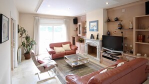 Un salon avec une cheminée, un canapé, une table basse et un téléviseur.
