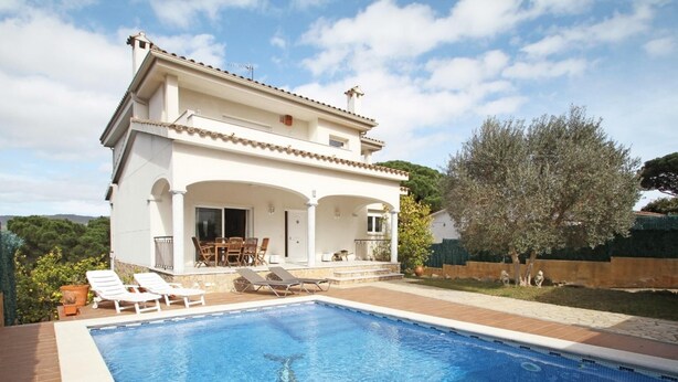Une maison à deux étages avec une piscine, du mobilier d’extérieur et une vue sur le paysage environnant.