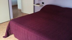 A room with a bed, a door, a wall-mounted shelf with a lamp, and a tiled floor. - Casa D Annunzio weekly discount + wi-fi (Pescara)