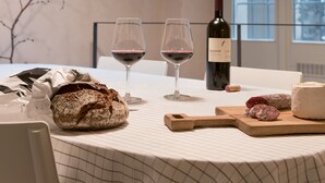 Ein Esstisch mit Brot, zwei Weingläsern, einer Weinflasche und einem Holztisch mit Käse und Fleisch.
