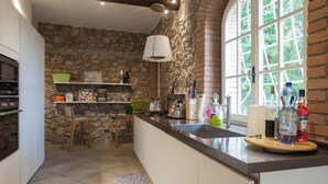 A kitchen with a stone wall, a large window, and a built-in oven. - La Dimora di Teresa: fairytale house in the woods, ideal for families with children. (Sovicille)