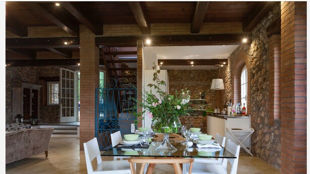 A dining area with a glass table, white chairs, and a vase of flowers. - La Dimora di Teresa: fairytale house in the woods, ideal for families with children. (Sovicille)