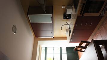 A kitchen with a window, cabinets, and a microwave.