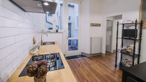 A modern kitchen with white tiles, a wooden countertop, a gas stove, and a black range hood. -  Casa Reali - Italian dream in Lucca, Toscany  (Lucca)