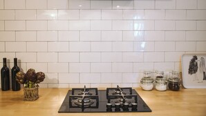 A kitchen with white tiled walls, a gas stove, and three wine bottles. -  Casa Reali - Italian dream in Lucca, Toscany  (Lucca)