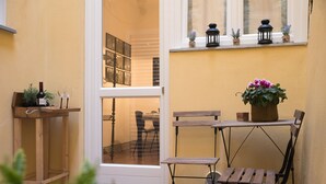 A wooden table and bench set against a yellow wall, with a window above and a door to the left. -  Casa Reali - Italian dream in Lucca, Toscany  (Lucca)