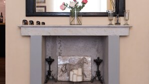 A fireplace with a mirror above it, a vase with flowers, and decorative items on the mantel. -  Casa Reali - Italian dream in Lucca, Toscany  (Lucca)