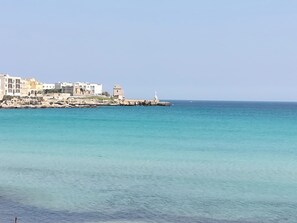 A coastal town with buildings along the shore, a lighthouse, and calm sea. - COMFORTABLE AND DELIGHTFUL THREE-ROOM APARTMENT ONE STEP FROM THE CASTLE OF OTRANTO (Otranto)