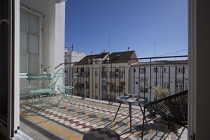 A balcony with a tiled floor, a table, and two chairs.