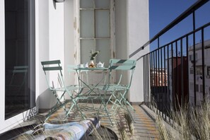 A balcony with a table and chairs, a window, and a railing.
