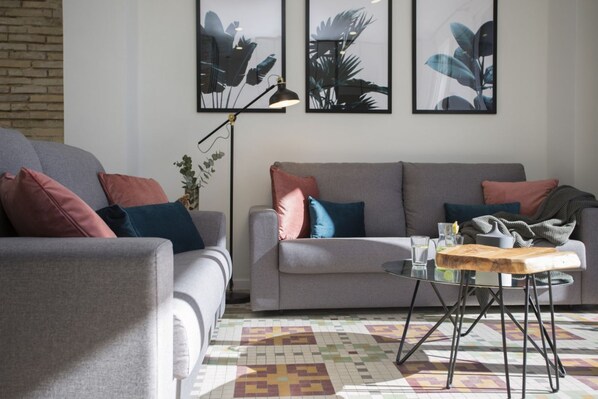 A living room with two grey sofas, a coffee table, and a patterned rug.