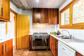 A compact kitchen with wooden cabinets, a stainless steel stove, and a white countertop.