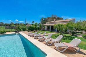A swimming pool with lounge chairs and a covered patio area.