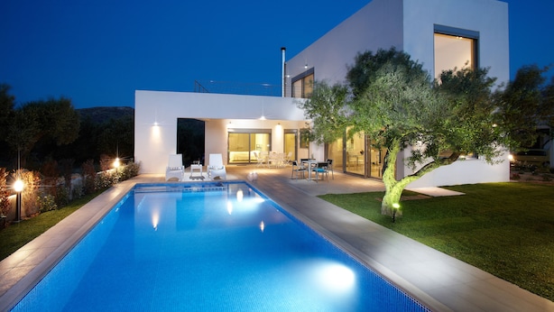 Une maison moderne dotée d’une piscine, d’un espace salon extérieur et d’un patio bien éclairé.