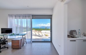 Enjoy a serene view from the balcony, featuring a glass desk, flat-screen TV, and kitchenette.