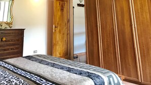 A bedroom with a wooden ceiling, a bed with patterned bedding, a wardrobe, and a mirror. - Andrea's House. Cls to all amenities. (Firenze)