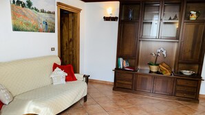 A living room with a beige sofa, a wooden cabinet, and a painting on the wall. - Andrea's House. Cls to all amenities. (Firenze)