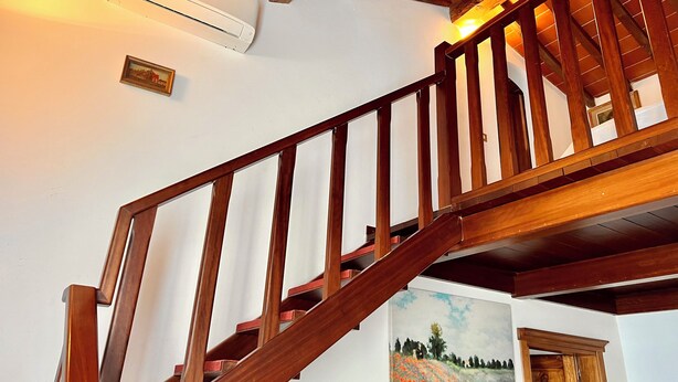 A wooden staircase with a handrail, an air conditioning unit mounted on the wall, and a painting of a landscape on the adjacent wall. - Andrea's House. Cls to all amenities. (Firenze)