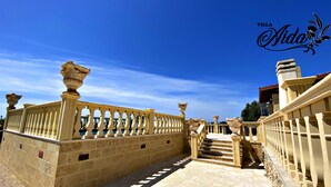Un sentiero in pietra conduce a una scalinata con balaustre e vasi decorativi.