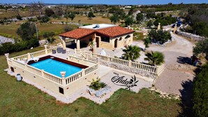 Una villa con piscina, patio coperto e vialetto in pietra.