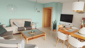 A living room with a sofa, coffee table, TV, and dining table with chairs. - OLIMPO PENTHOUSE WITH SEA VIEWS 5 MINUTES FROM THE BEACH. (Málaga)