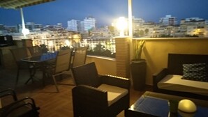 A rooftop terrace with outdoor seating, a view of the cityscape, and a brick wall. - OLIMPO PENTHOUSE WITH SEA VIEWS 5 MINUTES FROM THE BEACH. (Málaga)