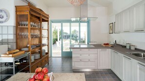 A modern kitchen with white cabinets, a built-in wine rack, and a large window. - Villa with pool, 450 metres from sea, near Trapani, Sicily - 14 pax (Paceco)