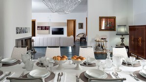 A dining area with a white table set for a meal, a white sofa in the background, and a chandelier above. - Villa with pool, 450 metres from sea, near Trapani, Sicily - 14 pax (Paceco)