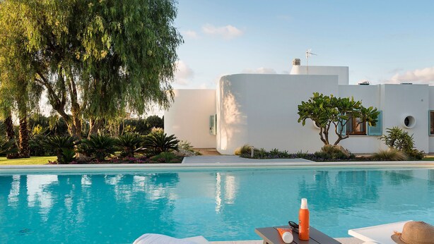 A swimming pool with lounge chairs and a table, surrounded by greenery and a modern building. - Villa with pool, 450 metres from sea, near Trapani, Sicily - 14 pax (Paceco)