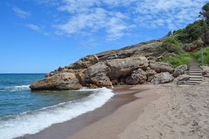 A beach with a rocky cliff, a staircase leading up, and a clear blue sky. - Ideal  for large families, quiet residential area , Sea views , Pool. (Sa Riera)