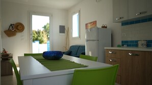 Una cocina moderna con armarios blancos, un refrigerador azul y una mesa de comedor con sillas verdes.
