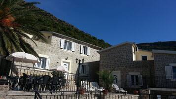 A stone building with a balcony, outdoor seating, and a pool area.