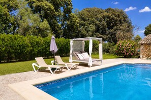 Une piscine avec des chaises longues et un auvent.