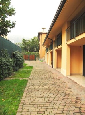 Un sendero que lleva a un edificio con fachada amarilla y un acceso cubierto.