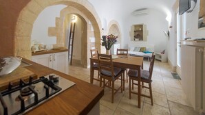 Una cocina compacta con estufa a gas, sillas de madera y una mesa de comedor.